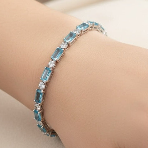 Riri Bespoke Jewelry tennis bracelet featuring rectangular blue topaz and diamond accents on a silver-tone chain.