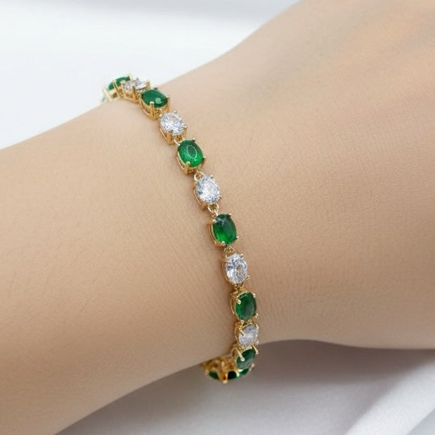 Riri Bespoke Jewelry gold tennis bracelet with alternating oval emerald-green stones and clear crystals on a wrist