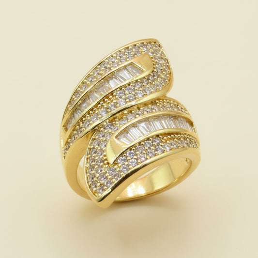 Riri Bespoke Jewelry gold-tone bypass statement ring with pave crystals and baguette-cut stones on a neutral background