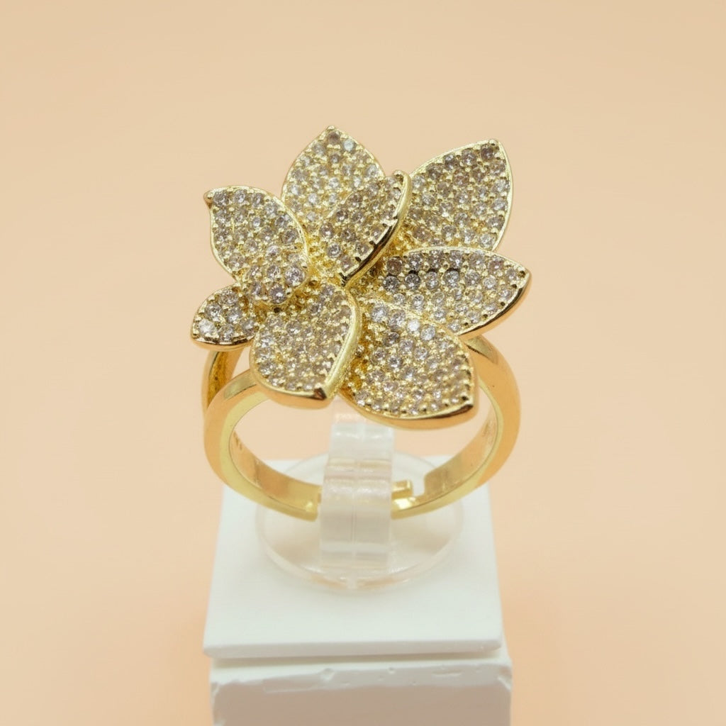 Riri Bespoke Jewelry gold-tone floral statement ring with shimmering cubic zirconia petals on a display stand.