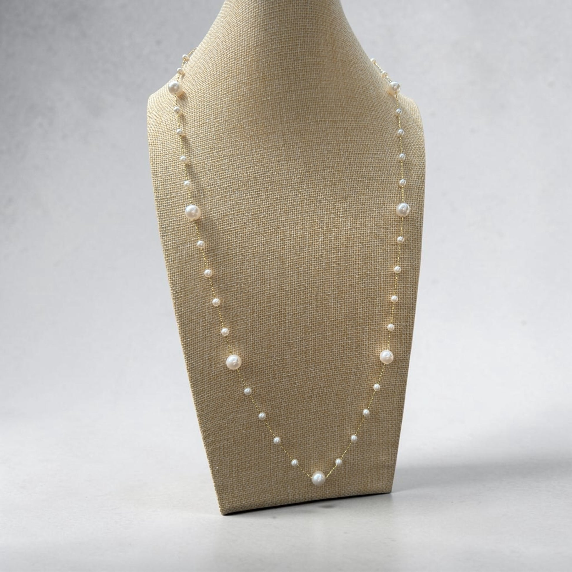 Riri Bespoke Jewelry long station necklace featuring lustrous white pearls spaced along a delicate gold-tone chain.