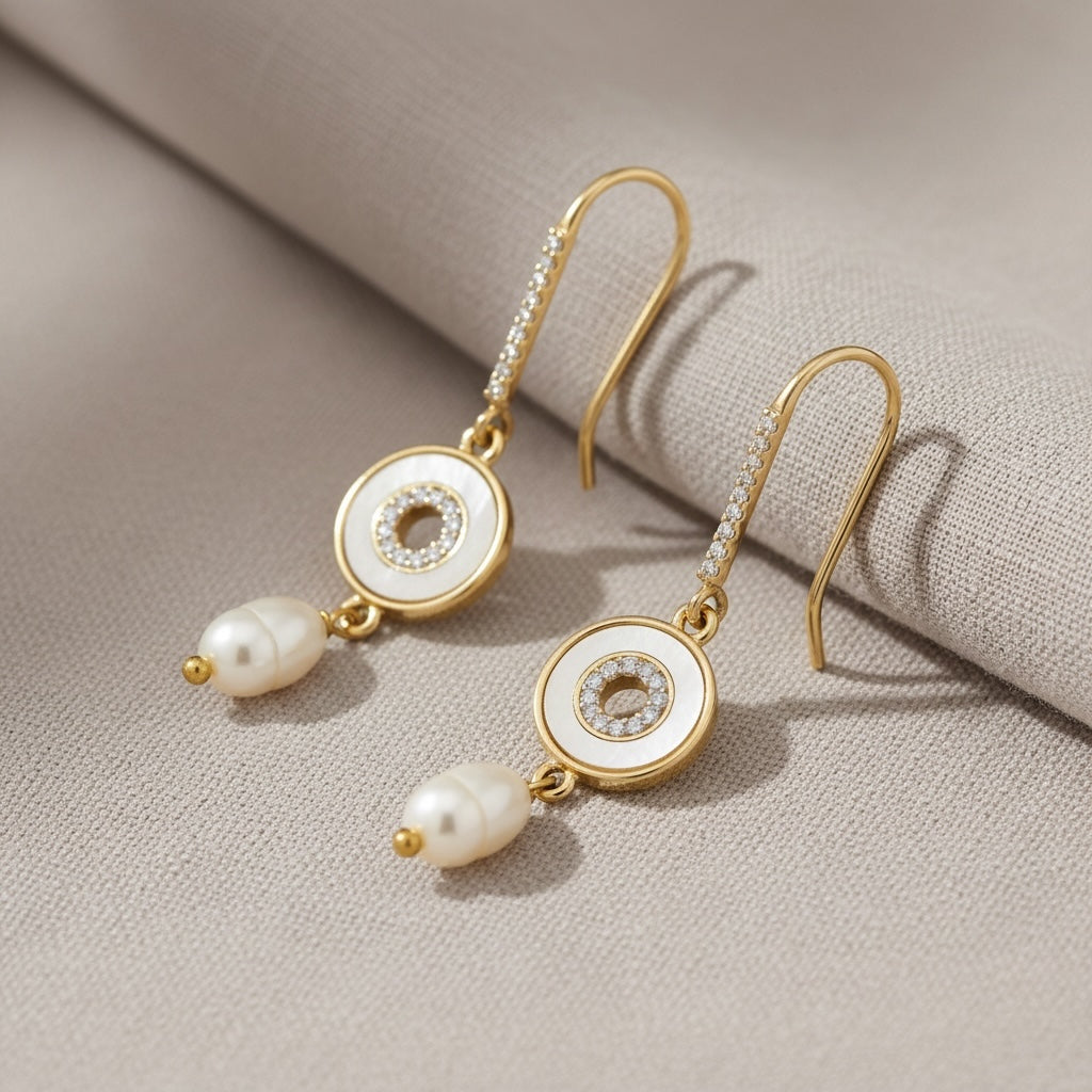 Riri Bespoke Jewelry gold drop earrings with mother-of-pearl circular accents, pavé crystals, and freshwater pearls.